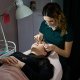 Una mujer que se arregla las cejas mientras usa parches oculares de hidrogel, mostrando un momento de cuidado personal y relajación.